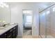 Bright bathroom featuring granite counters, dual sinks, a glass shower and doorway to a bedroom at 8940 Rhodes St, Kissimmee, FL 34747