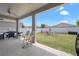 Covered back patio with white chairs and full outdoor kitchen overlooking the well-maintained yard at 9180 Carmela Ave, Davenport, FL 33897