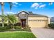 Charming single-story home features a two-car garage, stone accents and lush landscaping under a sunny sky at 9848 Nonacrest Dr, Orlando, FL 32832