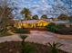 Inviting single-story home features lush landscaping and a circular driveway, beautifully lit at twilight at 12104 Lakeshore Dr, Clermont, FL 34711