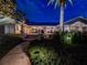 Charming single-story home with a well-lit walkway, lush landscaping, and a tall palm tree against a dark blue sky at 12104 Lakeshore Dr, Clermont, FL 34711