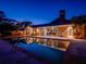 Inviting pool and patio area with outdoor dining and expansive glass windows reflecting the house at twilight at 12104 Lakeshore Dr, Clermont, FL 34711