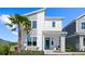 Modern two-story home with a blue door, complemented by a palm tree and manicured landscaping at 2026 Education St, St Cloud, FL 34771