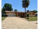 Charming single-story home with a spacious driveway, a well-manicured lawn, and a beautiful palm tree at 210 Dartmouth St, Deltona, FL 32725