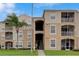 Tan condo building with a center stairwell, screened patios and well manicured lawn at 2305 Butterfly Palm # 102, Kissimmee, FL 34747