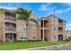 A tan, multi-story condo building with screened patios and a well-maintained lawn at 2305 Butterfly Palm # 102, Kissimmee, FL 34747