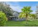 Manicured lawn surrounds this gray house with mature landscaping and features including palm trees and a covered patio at 2405 Abalone Blvd, Orlando, FL 32833