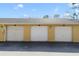 Picture of the garage with three bays, white doors, and yellow siding against a blue sky at 2624 Robert Trent Jones Dr # 634, Orlando, FL 32835