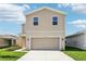 Tan two-story home with a two-car garage, a well-manicured lawn, and a concrete driveway at 3507 Salvia Ct, Tavares, FL 32778