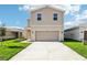 Tan two-story home with a two-car garage, a well-manicured lawn, and a concrete driveway at 3507 Salvia Ct, Tavares, FL 32778