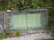 Aerial view of a green, well-maintained tennis court with surrounding greenery and parking lot at 4117 Fairview Vista Pt # 105, Orlando, FL 32804