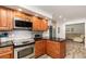 Functional kitchen with stainless steel appliances, wooden cabinetry, dark granite counters, and views into an adjacent room at 445 Autumn Oaks Pl, Lake Mary, FL 32746