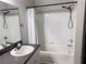 Bathroom showcasing a tub-shower combo with white tile, adjacent to a vanity with dark counters at 6408 Raleigh St # 2402, Orlando, FL 32835