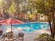 Community pool with lounge chairs, patio, lush landscaping, shade trees and table with chairs at 6408 Raleigh St # 2402, Orlando, FL 32835