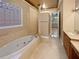 Bright bathroom featuring a jacuzzi tub, glass block window, and tiled walls at 8348 Via Rosa, Orlando, FL 32836