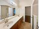 Bathroom featuring double sinks, a large mirror, and a doorway leading to a bedroom at 8348 Via Rosa, Orlando, FL 32836