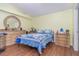 Cozy bedroom featuring wood-look floors, a round mirror, and a comfortable bed with blue floral bedding at 8982 Fort Jefferson Blvd, Orlando, FL 32822