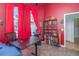 Vibrant red bedroom with a dark desk, a large window, and a bookshelf filled with books and figurines at 8982 Fort Jefferson Blvd, Orlando, FL 32822