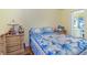 Bright bedroom featuring wood-look floors, a comfortable bed with blue floral bedding, and a view of the ensuite bathroom at 8982 Fort Jefferson Blvd, Orlando, FL 32822