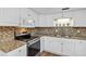 Galley kitchen featuring stainless appliances, granite countertop, tile backsplash, and wood-look floors at 1026 Woodall Dr, Altamonte Springs, FL 32714