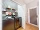 Well-lit laundry room features black washer/dryer, wood floors, decorative wallpaper, and shelving at 14143 Ancilla Blvd, Windermere, FL 34786