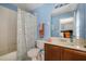 Cozy bathroom with blue walls, a vanity, a toilet, and a shower with a floral curtain at 14203 Avenue Of The Grvs, Winter Garden, FL 34787