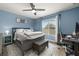 Bright blue bedroom with a ceiling fan, comfortable bed, and workspace by the window at 14203 Avenue Of The Grvs, Winter Garden, FL 34787