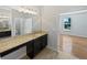 Bathroom vanity with granite counters, a large mirror, and access to a bedroom and half-bath at 1536 Softshell St, St Cloud, FL 34771