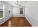 Bright bedroom with wood floors, a ceiling fan, and two large windows overlooking the front yard at 1536 Softshell St, St Cloud, FL 34771