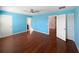 A blue primary bedroom features wood-look flooring, a ceiling fan, and three doorways at 1536 Softshell St, St Cloud, FL 34771