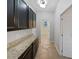 Hallway with granite counters, dark wood cabinets, and neutral tile flooring, connecting different areas of the home at 1536 Softshell St, St Cloud, FL 34771