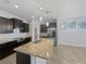 Modern kitchen boasts dark cabinets, granite countertops, stainless steel appliances, and a large island with a sink at 1536 Softshell St, St Cloud, FL 34771