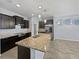 Kitchen with dark cabinets, granite counters, stainless appliances, an island with a sink, and modern pendant lighting at 1536 Softshell St, St Cloud, FL 34771