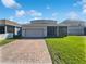 Home's rear exterior with brick driveway, attached two-car garage, and green lawn at 1536 Softshell St, St Cloud, FL 34771