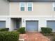 Charming townhouse exterior with blue garage door, brick driveway, and manicured landscaping, offering curb appeal at 2033 Milkweed St, Ocoee, FL 34761