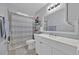 Well-lit bathroom features a shower with striped curtain, white vanity, and stylish mirror at 211 Dalton Dr, Kissimmee, FL 34758