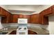 Functional kitchen featuring brown cabinetry, a white microwave and stove at 2446 Temple Grove Ln, Kissimmee, FL 34741