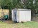 Outdoor storage shed surrounded by greenery, featuring a gray door and white siding at 2626 Balkan St, Apopka, FL 32703