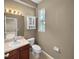 Well-lit bathroom featuring a single sink vanity, toilet, cabinet, and a window offering natural light at 2840 Grasmere View Pkwy, Kissimmee, FL 34746