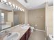 Bright bathroom featuring a large mirror, double sink, and a shower and tub combo at 2840 Grasmere View Pkwy, Kissimmee, FL 34746