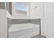 Bright, clean bathroom featuring a soaking tub with gray tile and a window at 2993 Irish Peach Dr, Winter Garden, FL 34787