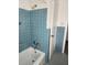 Bathroom featuring blue tiled walls, a white bathtub and shower, and a white door at 3112 Eleuthera Ln, Orlando, FL 32827