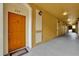 A hallway view with unit 208 featuring a bright orange door and decorative sconce lighting at 3338 Robert Trent Jones Dr # 20804, Orlando, FL 32835