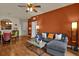 A living room with hardwood floors features an orange accent wall, gray couch and a ceiling fan at 3338 Robert Trent Jones Dr # 20804, Orlando, FL 32835