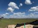 Scenic view from construction site overlooking grassy field and waterfront, under a blue sky with scattered clouds at 336 Caladium Ave, Lake Alfred, FL 33850