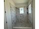 Contemporary shower with elegant marble-look walls and a stone-pebbled floor, blending luxury with modern design at 336 Caladium Ave, Lake Alfred, FL 33850