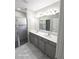 Bathroom featuring double sinks, elegant vanity, shower, and large mirror with vanity lighting at 3869 Carrick Bend, Kissimmee, FL 34746