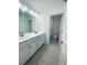 Bathroom featuring double vanities with white countertops, a large mirror, and access to a separate toilet room at 5961 Vision Rd, St Cloud, FL 34771