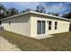 Rear exterior view of home featuring neutral stucco, sliding glass doors, and manicured lawn at 950 20Th St, Orlando, FL 32805