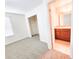 This bedroom features neutral walls, carpet, a window with blinds, and a view into the attached bathroom at 1132 Chelsea Dr, Davenport, FL 33897